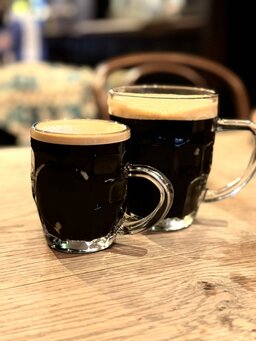 A pint and a half of dark beer in handled glasses