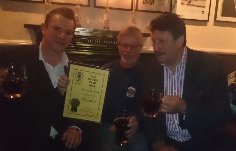 Jonathan Tingle (left) and Stuart Gale (right and father of licensee Nicole Gale) accept the 2014 North London Pub of the Year Award from John Cryne. 