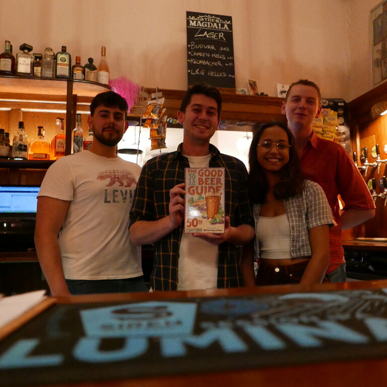 The team behind the bar display their Good Beer Guide 2023 to celebrate their listing.