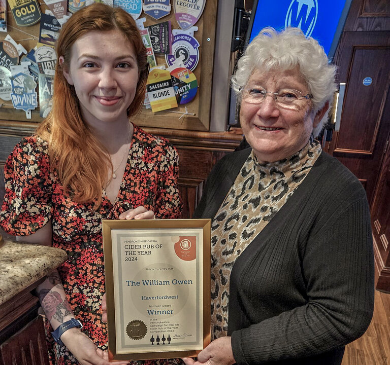 Pub manager Nicola Morris accepts the William Owen's 2024 CAMRA Cider Pub of the Year award from Alwen Thomas.