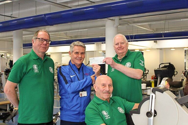 Robin Shields, left, and John Corser, right, present a cheque to Russell Tipson as Terry Astley demonstrates how the exercise machines are helping his rehabilitation.