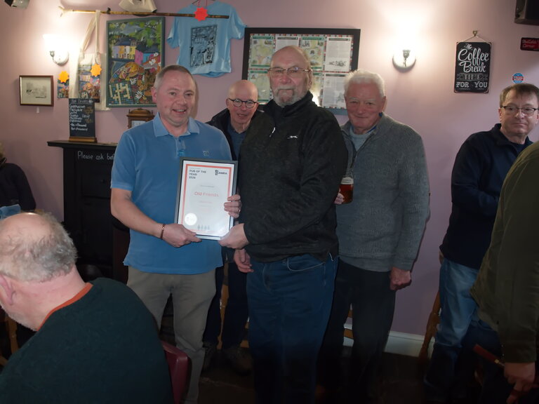 Terry Ridal from Furness CAMRA presents the Branch Pub of the Year 2026 Finalist Certificate to Graham Wilson of The Old Friends in Ulverston. This year was a very close run contest and this is a well-deserved accolade for the Pub. You notice a number of Branch members lurking in the background all enjoying some of Graham's selection of cask ales. Terry Ridal from Furness CAMRA presents the Branch Pub of the Year 2026 Finalist Certificate to Graham Wilson of The Old Friends in Ulverston. This year was a very close run contest and this is a well-deserved accolade for the Pub. You notice a number of Branch members lurking in the background all enjoying some of Graham's selection of cask ales.
