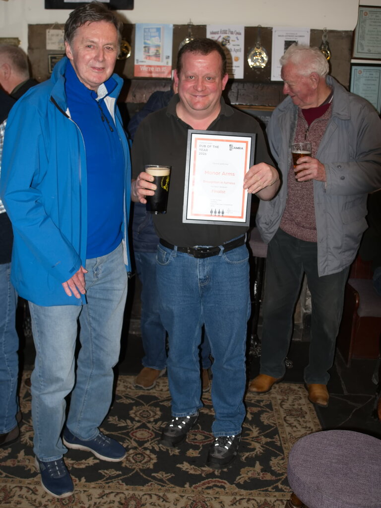 Scott Varty of The Manor Arms Broughton-in-Furness receives the Certificate for Finalist - Furness Pub of the Year 2026 from member Ken Parr with Peter Gardner, another Branch member, looking on. Scott Varty of The Manor Arms Broughton-in-Furness receives the Certificate for Finalist - Furness Pub of the Year 2026 from member Ken Parr with Peter Gardner, another Branch member, looking on.